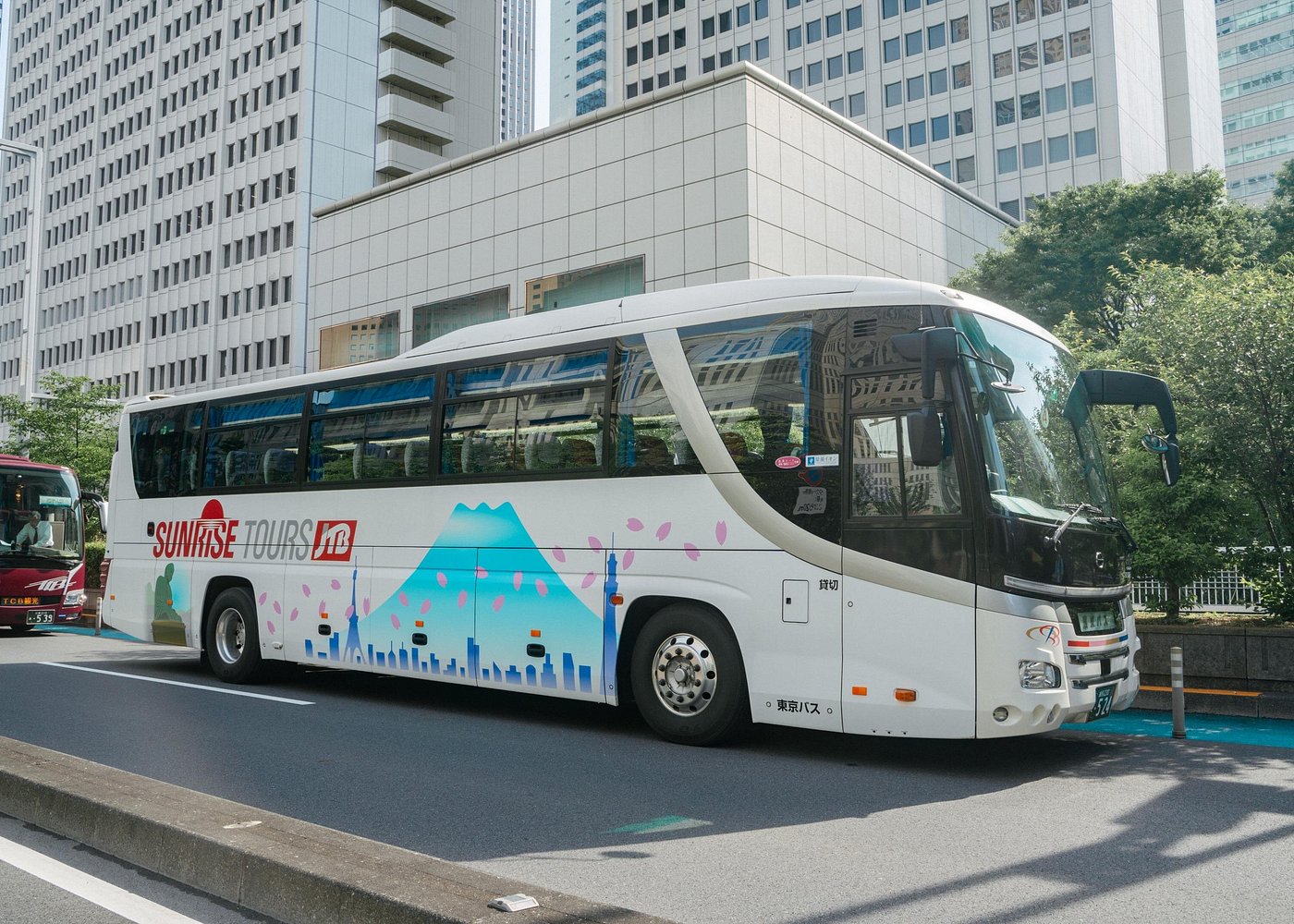White JTB Sunrise Tours coach on a Tokyo street, with a Mount Fuji graphic along the side